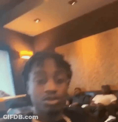 A Man Is Taking A Selfie In A Restaurant While Sitting At A Table . GIF