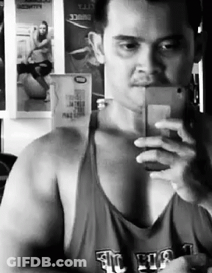 A Man Is Taking A Selfie In Front Of A Mirror . GIF