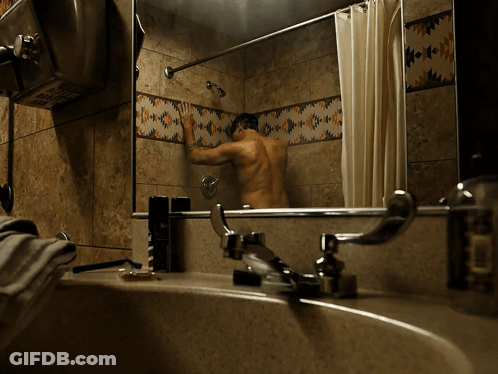 A Man Is Taking A Shower In A Bathroom With Native American Tiles GIF