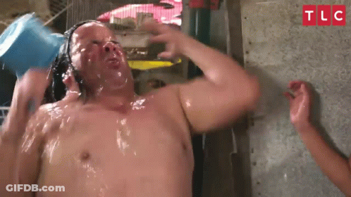 A Man Is Taking A Shower With A Bucket Of Water On His Head .. GIF