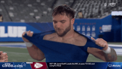 A Man Is Taking Off His Shirt While Watching A Football Game On Prime GIF