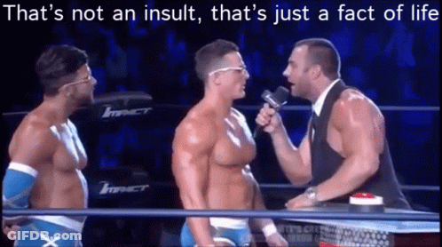 A Man Is Talking Into A Microphone In A Wrestling Ring While Two Other Men Look On . GIF