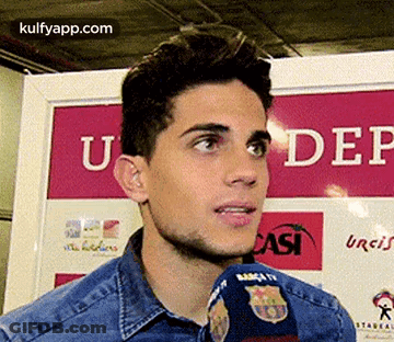 A Man Is Talking Into A Microphone In Front Of A Sign That Says Under GIF