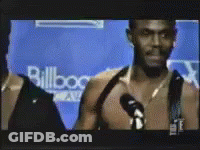 A Man Is Talking Into A Microphone In Front Of A Wall That Says Billboard GIF