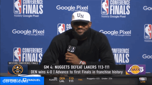 A Man Is Talking Into A Microphone In Front Of A Wall That Says Conference Finals On It GIF