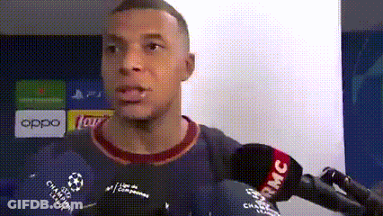 A Man Is Talking Into A Microphone While Wearing A Blue Shirt With A Soccer Ball On It . GIF