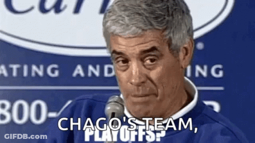 A Man Is Talking Into A Microphone While Wearing A Blue Sweater And A White Shirt . GIF