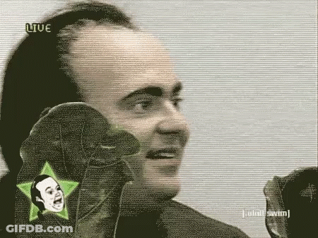 A Man Is Talking Into A Microphone While Wearing A Pair Of Gloves With A Star On It . GIF