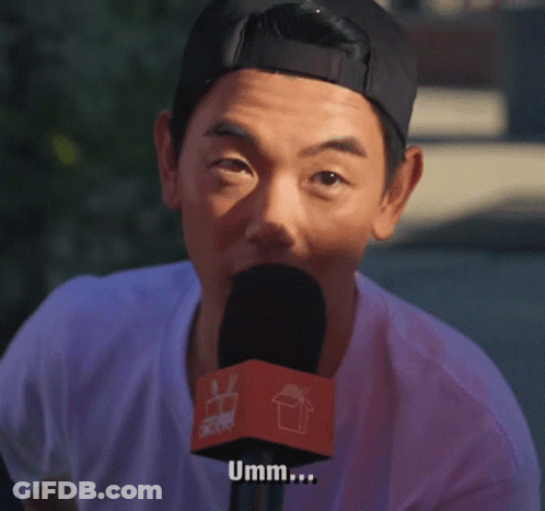 A Man Is Talking Into A Microphone With The Word Umm Written On It GIF