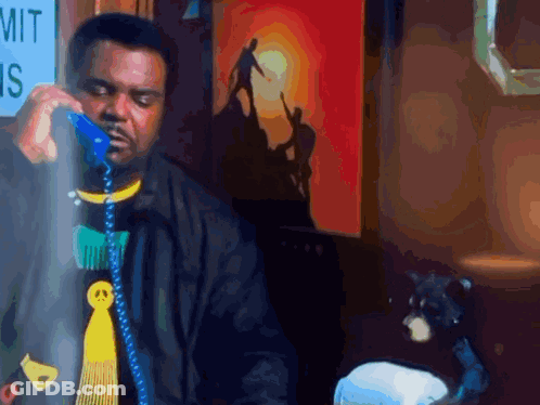 A Man Is Talking On A Blue Phone In Front Of A Sign That Says Mit GIF