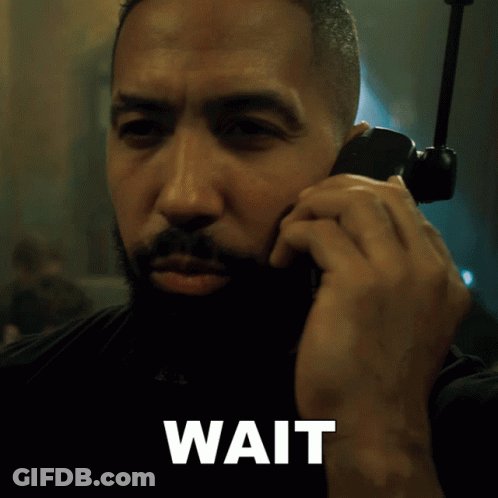 A Man Is Talking On A Cell Phone And The Word Wait Is Below Him GIF