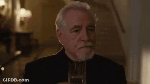 A Man Is Talking On A Cell Phone In A Room With A Chandelier In The Background . GIF