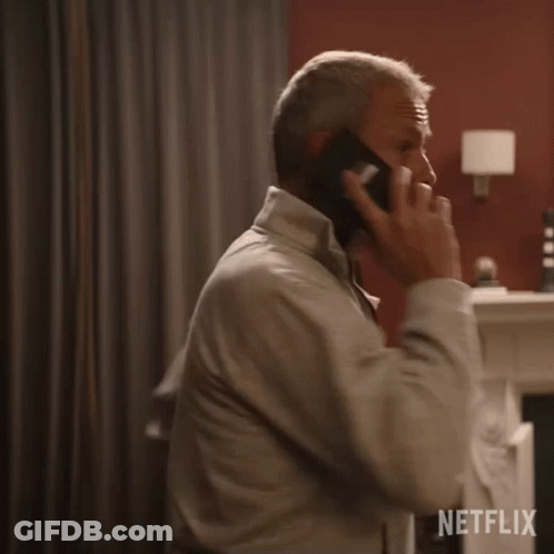 A Man Is Talking On A Cell Phone In A Room With A Netflix Logo In The Corner GIF