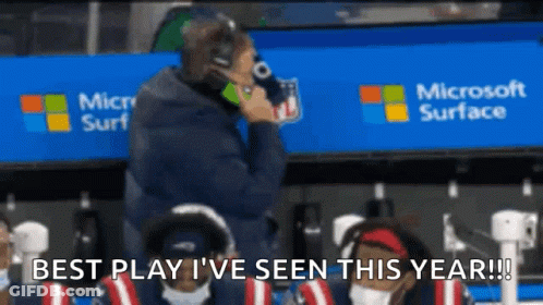A Man Is Talking On A Cell Phone In Front Of A Microsoft Surface Sign GIF