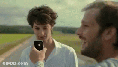 A Man Is Talking On A Cell Phone While Another Man Looks On . GIF