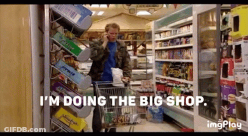 A Man Is Talking On A Cell Phone While Pushing A Shopping Cart In A Grocery Store . GIF