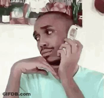 A Man Is Talking On A Cell Phone While Sitting Down . GIF