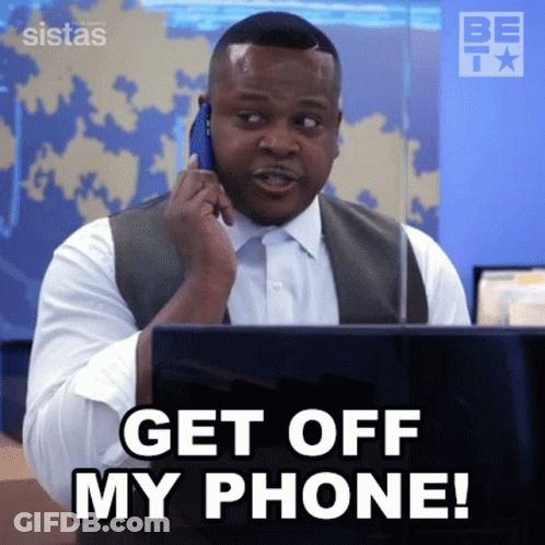 A Man Is Talking On A Cell Phone While Sitting In Front Of A Laptop . GIF