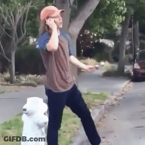 A Man Is Talking On A Cell Phone While Standing Next To A Fire Hydrant . GIF