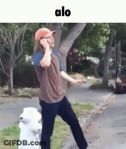 A Man Is Talking On A Cell Phone While Standing Next To A White Fire Hydrant . GIF