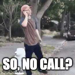 A Man Is Talking On A Cell Phone While Walking Down A Sidewalk . GIF