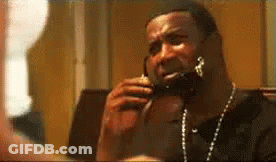 A Man Is Talking On A Cell Phone While Wearing A Necklace . GIF