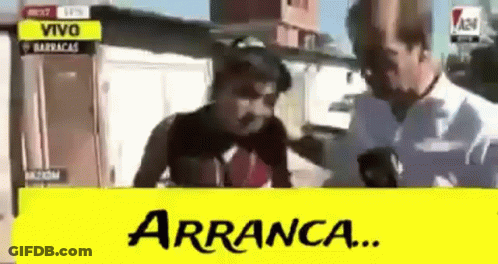 A Man Is Talking On A Cell Phone With A Yellow Sign That Says Arranca . GIF