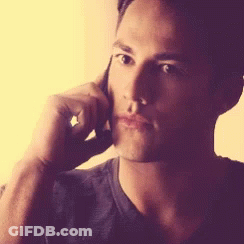A Man Is Talking On A Cell Phone With His Hand On His Face GIF