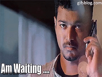 A Man Is Talking On A Cell Phone With The Words Am Waiting Behind Him GIF