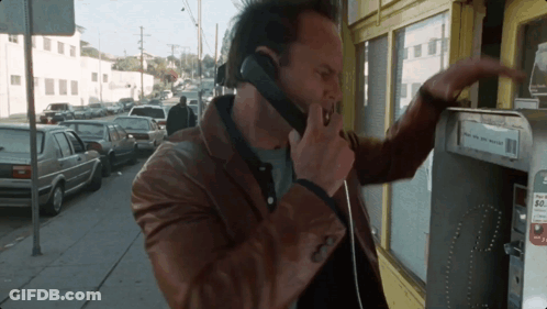 A Man Is Talking On A Pay Phone With A Sign That Says ' Pay Here And Get Paid ' On It GIF