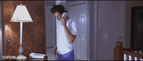 A Man Is Talking On A Phone In A Dark Room GIF