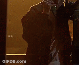 A Man Is Talking On A Phone In Front Of A Window With Rain Drops On It GIF