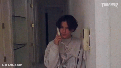 A Man Is Talking On A Telephone In A Hallway . GIF
