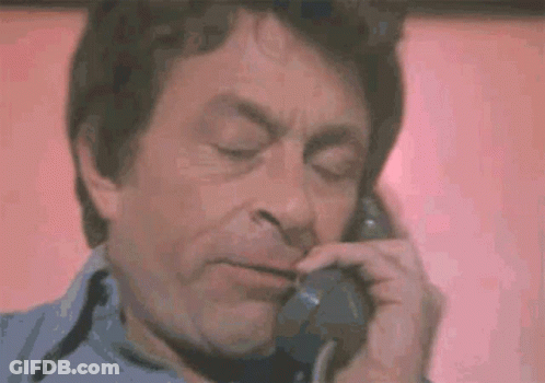 A Man Is Talking On A Telephone With His Eyes Closed And His Mouth Open . GIF