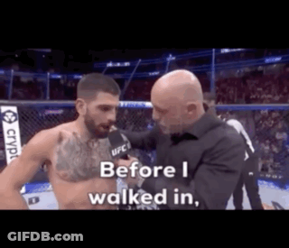 A Man Is Talking To Another Man In A Boxing Ring While A Referee Looks On . GIF