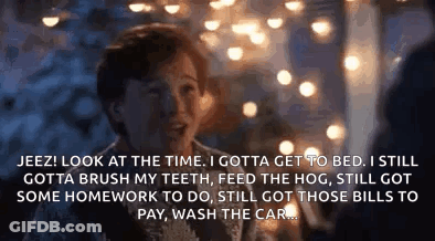 A Man Is Talking To Another Man In Front Of A Christmas Tree While Sitting At A Table . GIF