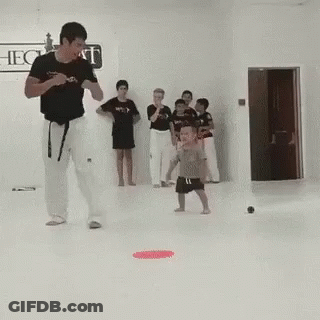 A Man Is Teaching A Child How To Kick A Ball In A Karate Class . GIF