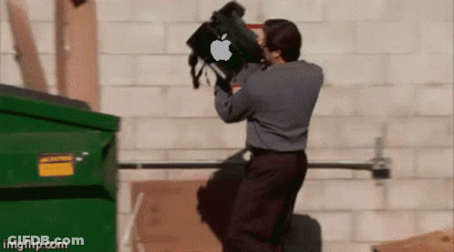 A Man Is Throwing A Bag With An Apple Logo On It Into A Dumpster GIF