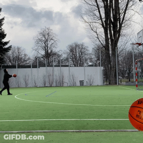 A Man Is Throwing A Ball On A Basketball Court With A Spalding Ball In The Foreground GIF