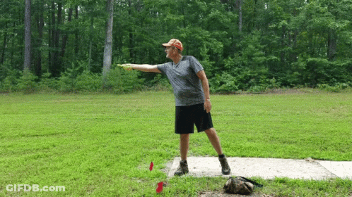 A Man Is Throwing A Frisbee In A Grassy Field GIF