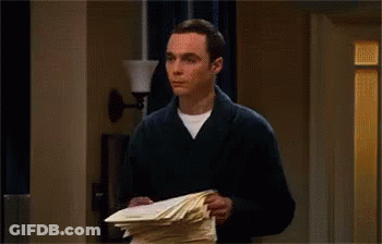 A Man Is Throwing Papers In The Air While Standing In A Hallway . GIF