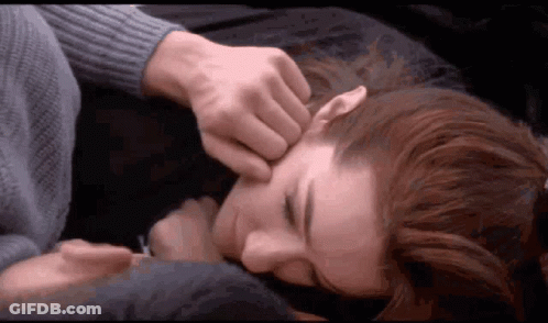 A Man Is Touching A Woman 'S Face While Laying On A Bed GIF