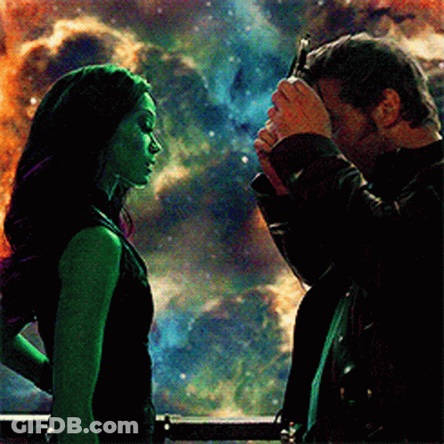 A Man Is Touching A Woman 'S Forehead In Front Of A Galaxy . GIF