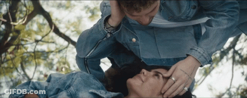 A Man Is Touching A Woman 'S Forehead While Laying Down GIF