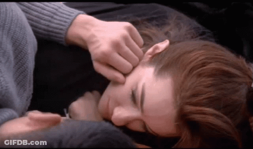 A Man Is Touching A Woman 'S Forehead While Laying On A Bed GIF