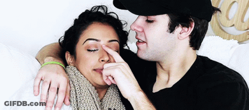 A Man Is Touching A Woman 'S Nose While Laying On A Bed GIF