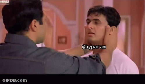 A Man Is Touching Another Man 'S Face In A Room . GIF