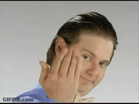 A Man Is Touching His Face With His Hands While Smiling . GIF