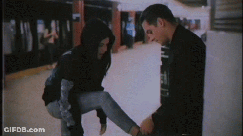 A Man Is Tying A Woman 'S Shoe In A Subway Station GIF