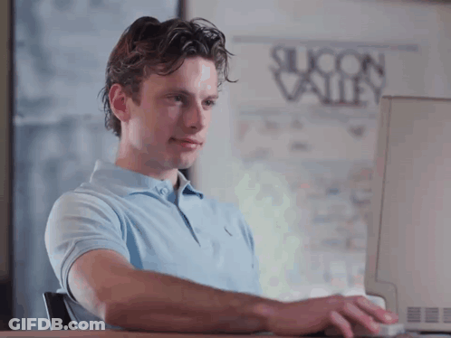 A Man Is Typing On A Computer In Front Of A Silicon Valley Poster GIF